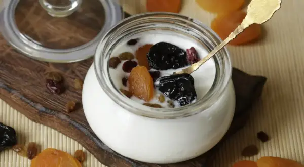 Jogurt z suszonymi owocami i złotą łyżeczką – idealne szybkie śniadanie na ciepło.