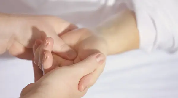 En hand masserar en annan handled, kanske för att lindra klåda gravid.