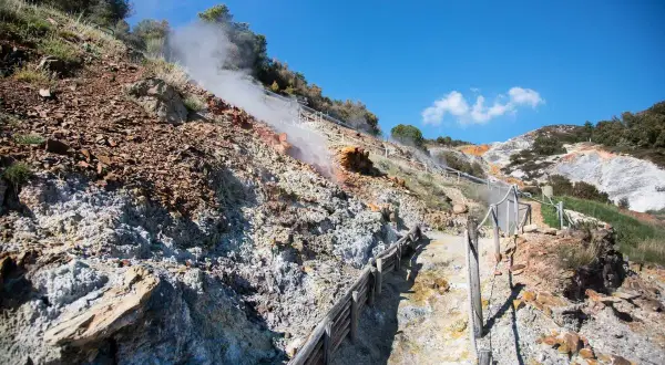 Sentiero nel **parco delle Biancane** con fumarole fumanti e rocce colorate.