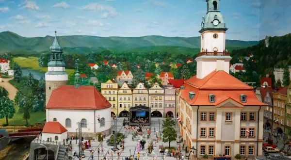 Miniaturowy rynek w Jeleniej Górze, z wieżą ratuszową, kamieniczkami i tłumem ludzi.
