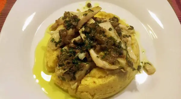 Delizioso luccio alla gardesana su un letto di polenta, condito con erbe aromatiche e olio d'oliva.