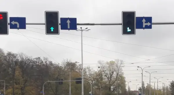 Sygnalizacja świetlna z zieloną strzałką do przodu i w prawo, zieloną strzałką do przodu, czerwoną strzałką w lewo. Znak S3 informuje o dozwolonych kierunkach jazdy.