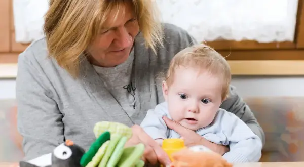 Babcia z czułością opiekuje się wnukiem, pokazując mu zabawki.
