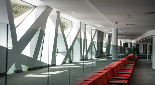 Nowoczesny korytarz z czerwonymi kanapami i geometrycznymi oknami. Hotel Narvil Conference & Spa opinie – idealne miejsce na wydarzenia.