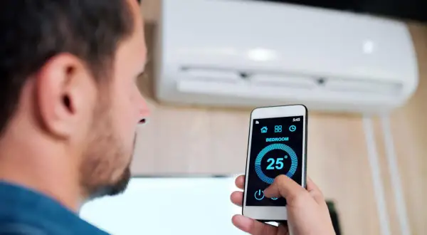 Uomo controlla condizionatore Mitsubishi con smartphone, mostrando come collegare condizionatore Mitsubishi wifi per gestire la temperatura da remoto.