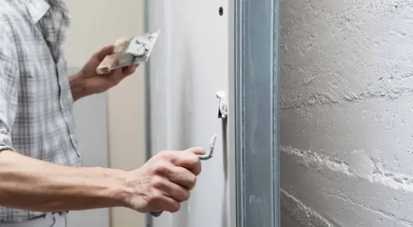 Un artisan applique un enduit de finition sur un mur avec une truelle, préparant la surface pour une peinture parfaite.