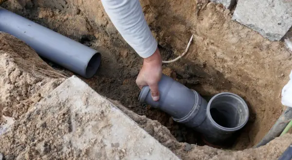 Hand verbindet ein Rohrstück mit einem Abzweig. Dies ist Teil der Installation, um die wasserleitung frostsicher isolieren zu können.