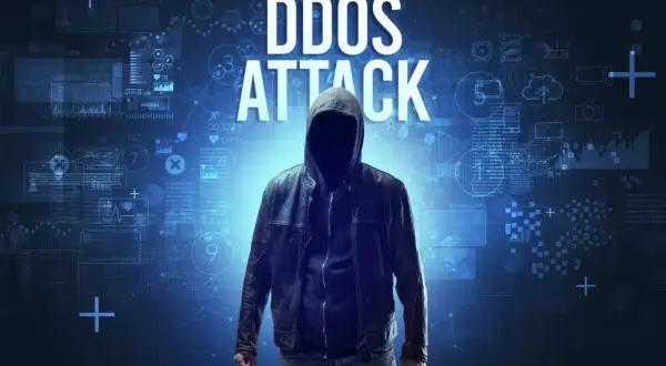 Anonimowa postać w kapturze i skórzanej kurtce, symbolizująca zagrożenie cybernetyczne, na tle cyfrowych danych i tekstu "DDOS ATTACK".
