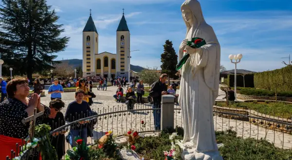 Pielgrzymi w Medziugorie modlą się przed figurą Matki Bożej. Przyczyny popularności Medziugorie mimo braku oficjalnego uznania dogmatu.