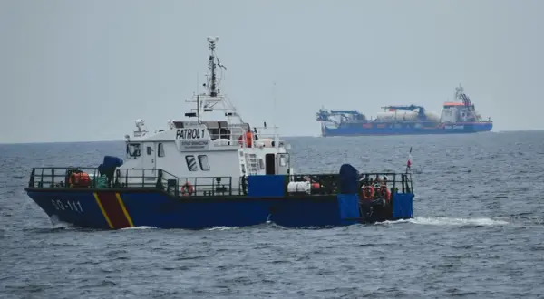Kuter Straży Granicznej "PATROL 1" płynie po morzu. W tle widać duży statek "Van Oord".