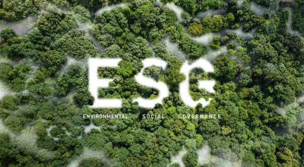 Foresta lussureggiante con la scritta "ESG" in bianco, che simboleggia investimenti ESG. Sotto, le parole "Environmental, Social, Governance".