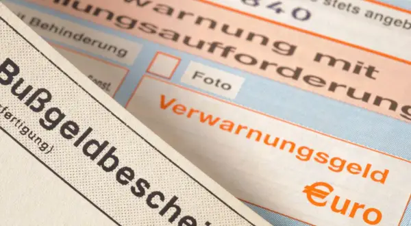 Zbliżenie na niemieckie mandaty, w tym "Bußgeldbescheid" i "Verwarnungsgeld" z symbolem euro.
