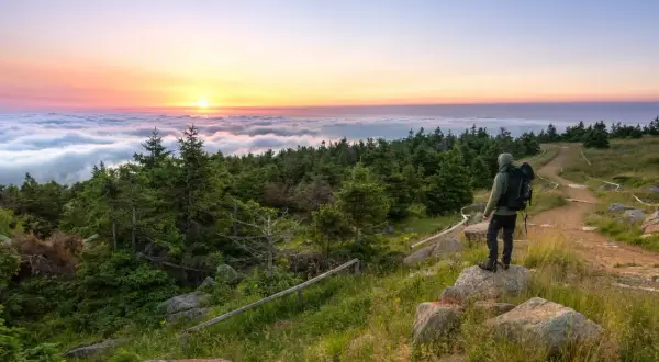 Wanderer genießt Sonnenaufgang über Wolkenmeer. Auf dem Brocken kann man wandern, die Natur bestaunen und den Ausblick genießen.