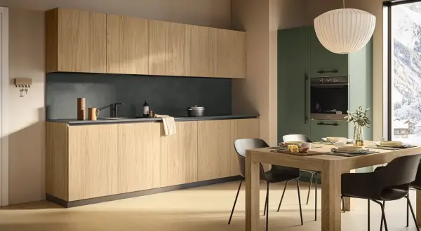Cucina moderna con mobili in legno chiaro e pensili alti. La zona pranzo è apparecchiata, con una vista panoramica innevata dalla finestra. L'altezza dei mobili cucina è ben studiata per funzionalità ed estetica.