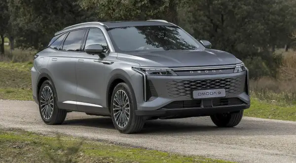 Szary OMODA 9 na drodze leśnej. Nowoczesny SUV z charakterystycznym grillem i światłami LED.