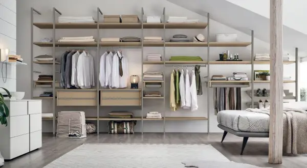 Una cabina armadio mansarda bassa, con scaffali in legno e metallo, ospita abiti ordinati e accessori.