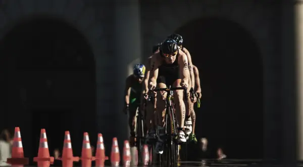 Athletes compete in an Olympic triathlon cycling race, focused and determined as they push forward.