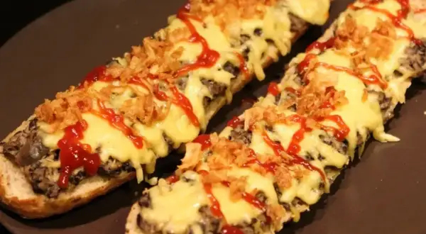 Dwie zapiekanki z airfryer na bagietce, z serem, chrupiącą cebulką i ketchupem.