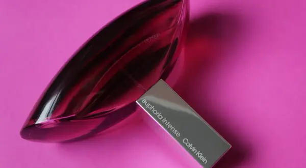 Perfumy Calvin Klein Euphoria Intense w szklanej, fioletowej butelce na różowym tle.