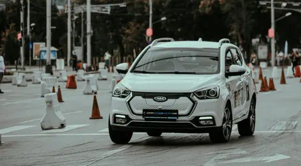 Voiture blanche lors d'un stage de sensibilisation à la sécurité routière, slalomant entre des cônes et des barrières.