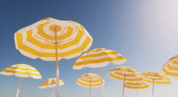 Gula och vita parasoller mot en klarblå himmel, en perfekt bild av arbetsfria dagar.