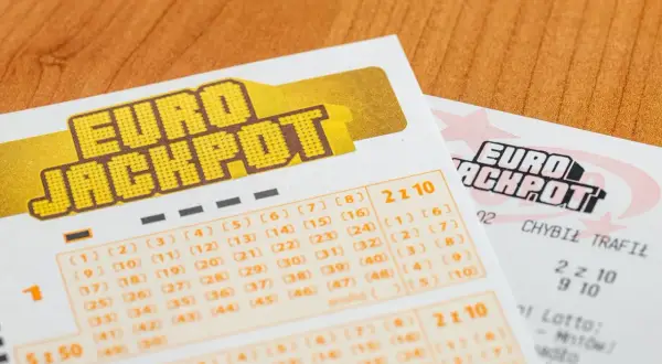 Kupony Eurojackpot na drewnianym tle. Zastanawiasz się, dlaczego Polska dołączyła do Eurojackpot tak późno w porównaniu do sąsiadów?