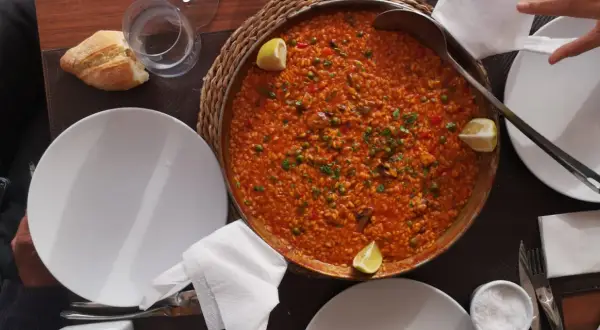 Paella mixta, un clásico que no puede faltar si te preguntas qué comer en Cabo de Gata. Servida en una paellera, con limón y pan.