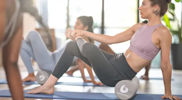 Donne in posa con rulli per pilates, un'immagine che cattura la dedizione al pilates fisico prima e dopo l'allenamento.