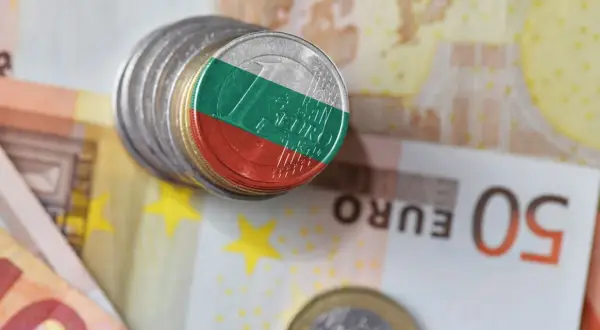 Monety z flagą Bułgarii na tle eurobanknotów. Waluta Bułgaria w kontekście europejskim.
