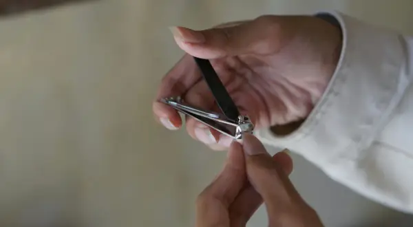 Une main utilise un coupe-ongles pour couper un ongle homme.