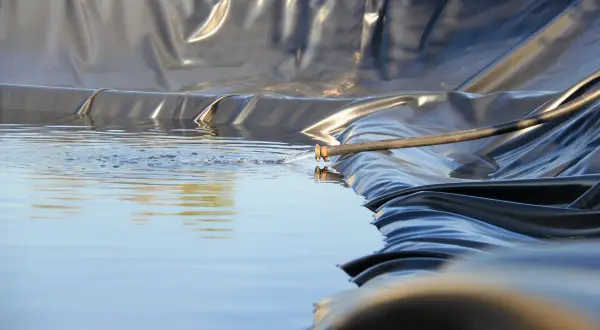 Wasser fließt aus einem Schlauch in einen neu angelegten Folienteich.