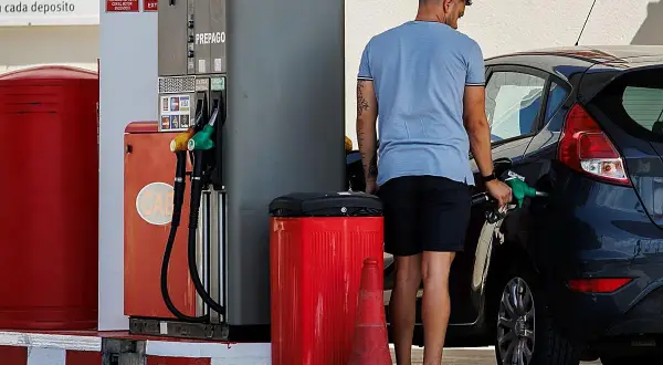 Hombre repostando su coche con gasolina 98. El surtidor muestra opciones de combustible, incluyendo la opción de alta octanaje.