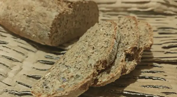 Wilgotny chleb orkiszowy, pokrojony w kromki, z widocznymi ziarnami. Idealny na śniadanie.