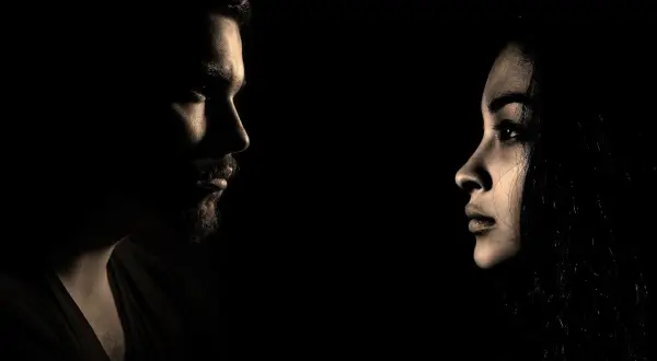 Profili di un uomo e una donna si fronteggiano nel buio, un'immagine che evoca il silenzio dopo la fine di una storia.