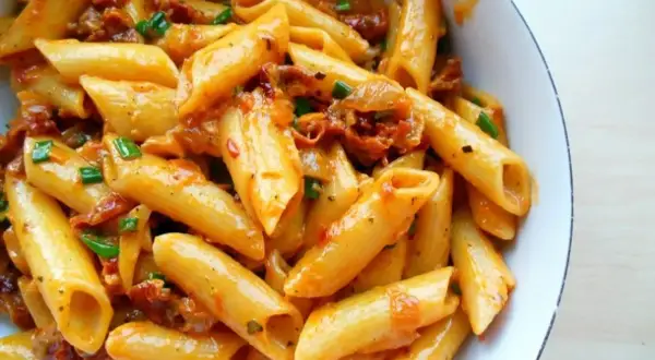 Penne z sosem z suszonych pomidorów, czosnku i ziół, posypane szczypiorkiem. Pyszne danie, które zachwyci każdego miłośnika makaronu.