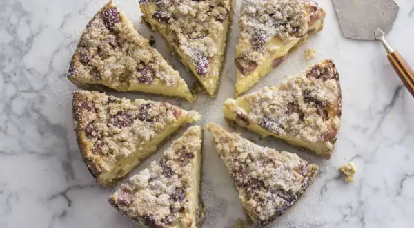 Süßer Rhabarber Schmand Kuchen, in Stücke geschnitten, mit Puderzucker bestäubt, auf Marmorplatte.