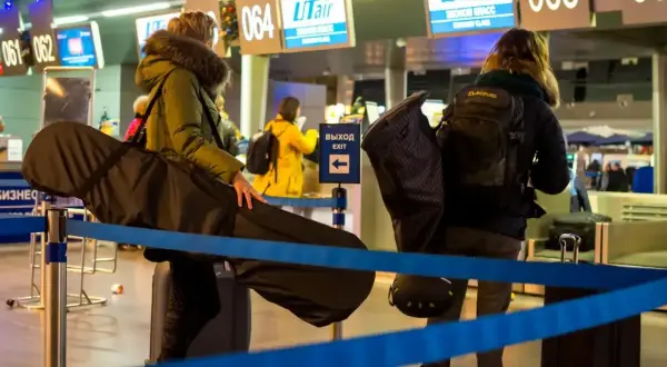 Osoby z bagażem sportowym Ryanair czekają w kolejce na lotnisku.