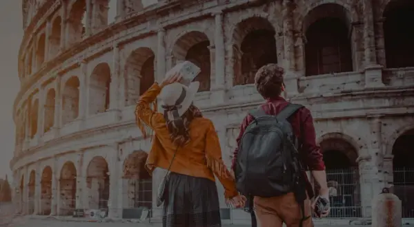 Ett par håller hand framför Colosseum i Rom. Trots att det är december är temperaturen behaglig för turister.