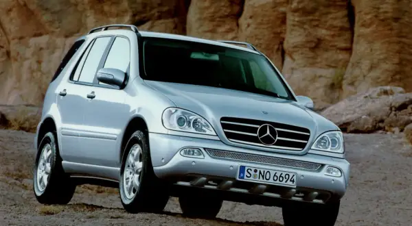 Srebrny Mercedes ML 320 na tle skalistego krajobrazu.