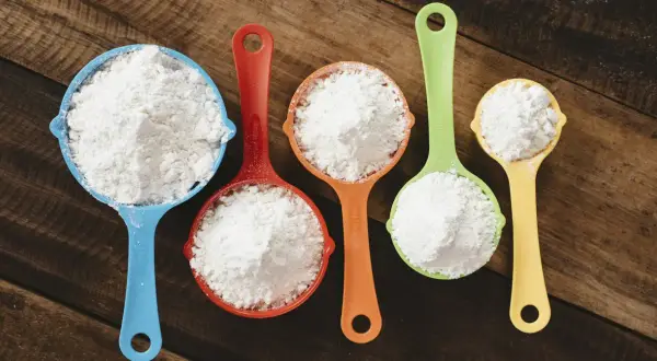 Mätkoppar med mjöl, redo att byta vetemjöl mot glutenfritt för bakning.