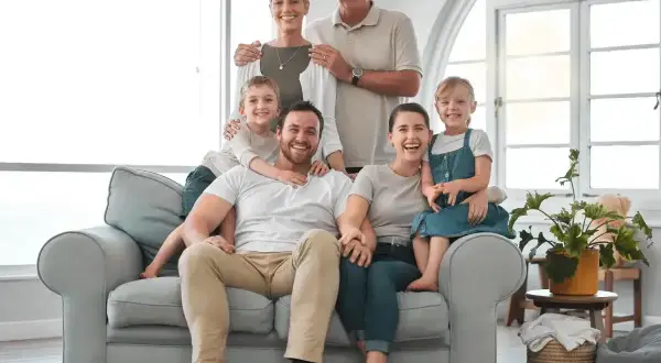 Uśmiechnięta, wielopokoleniowa rodzina siedząca na kanapie.