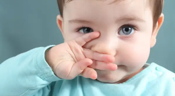 Niebieskooki maluch zasłania nosek rączką, sugerując brak apetytu u dziecka.