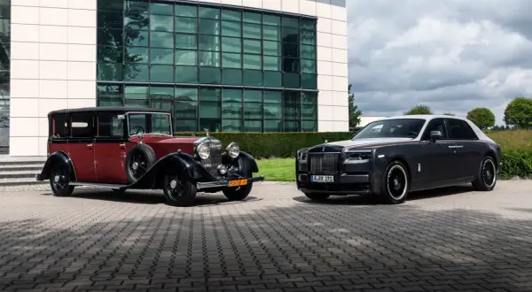 Dwa Rolls-Royce'y Phantom: zabytkowy czerwono-czarny i nowoczesny grafitowo-biały, stojące przed budynkiem.