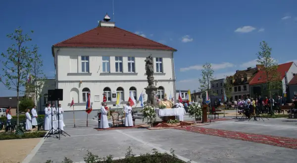 Uroczystość religijna na rynku w **Borku Wielkopolskim**. Kapłan odprawia mszę, towarzyszą mu ministranci i wierni.
