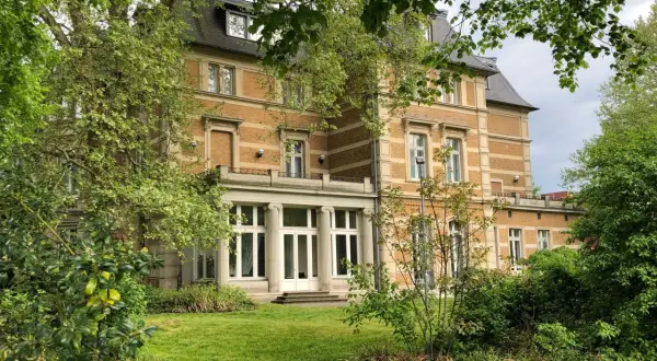 Prachtvolle Villa Zanders, umgeben von üppigem Grün, mit einem Weg, der sich durch den Garten schlängelt.