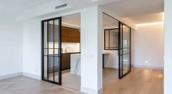 Puertas correderas de cristal negro separan la cocina moderna. Se planea poner baldas entre dos paredes para maximizar el espacio.