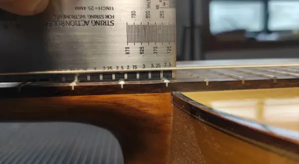 Ajustando la altura de las cuerdas de una guitarra flamenca con una regla de acción.