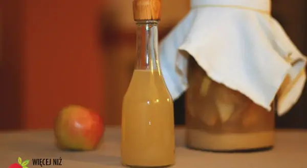 Butelka z octem jabłkowym, obok jabłko i słoik z fermentującymi jabłkami. Czy ocet jabłkowy zawiera alkohol?