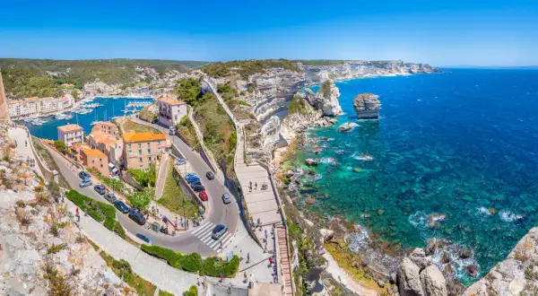 Vue panoramique de Bonifacio, Corse. La ville perchée sur les falaises blanches surplombe un port animé et une mer turquoise. Idéal pour visiter Bonifacio.