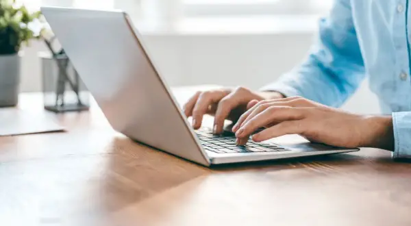 Osoba pisze na laptopie, korzystając z przeglądarki Opera GX z wbudowanym VPN.